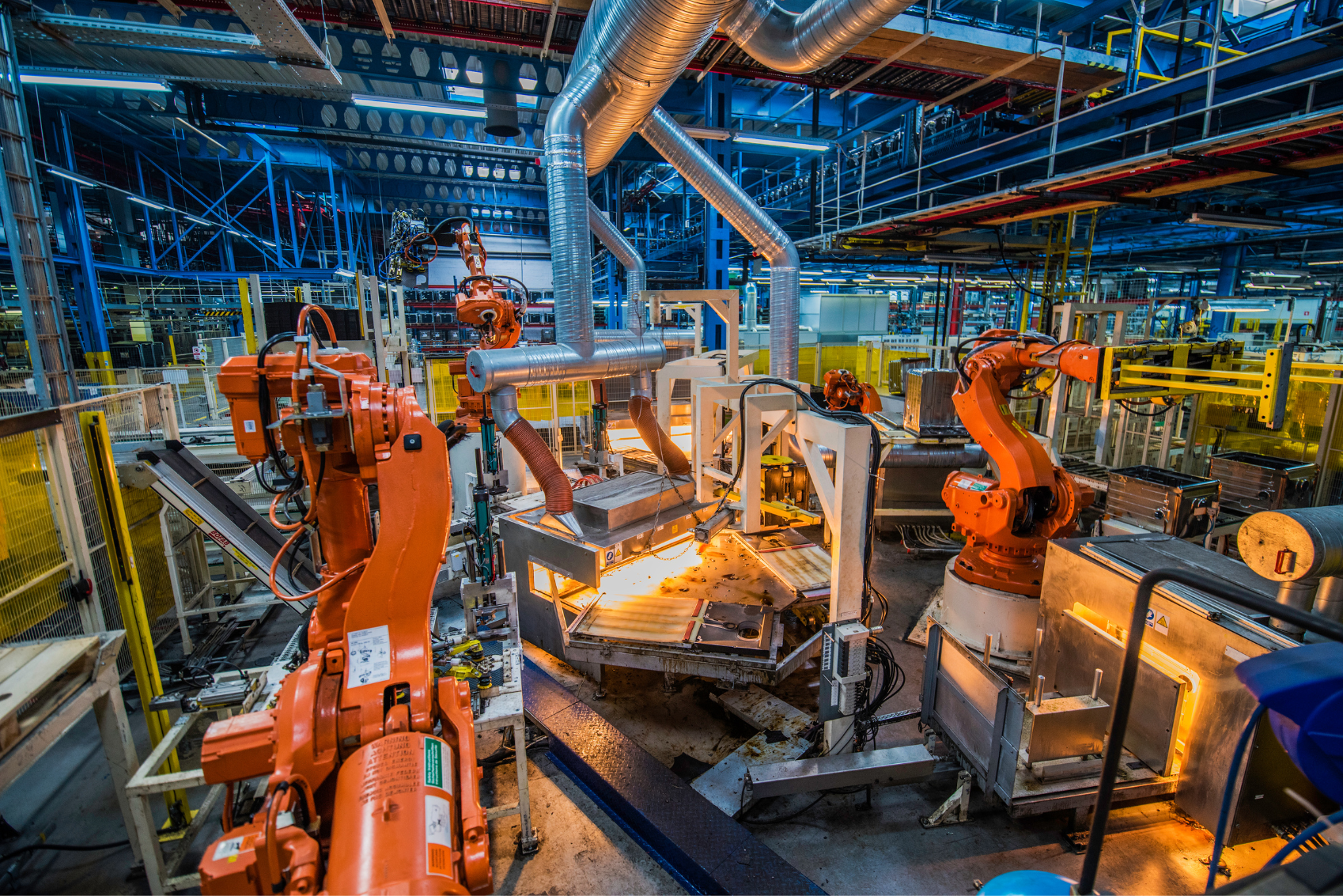 A factory with a lot of robots working on a piece of metal.