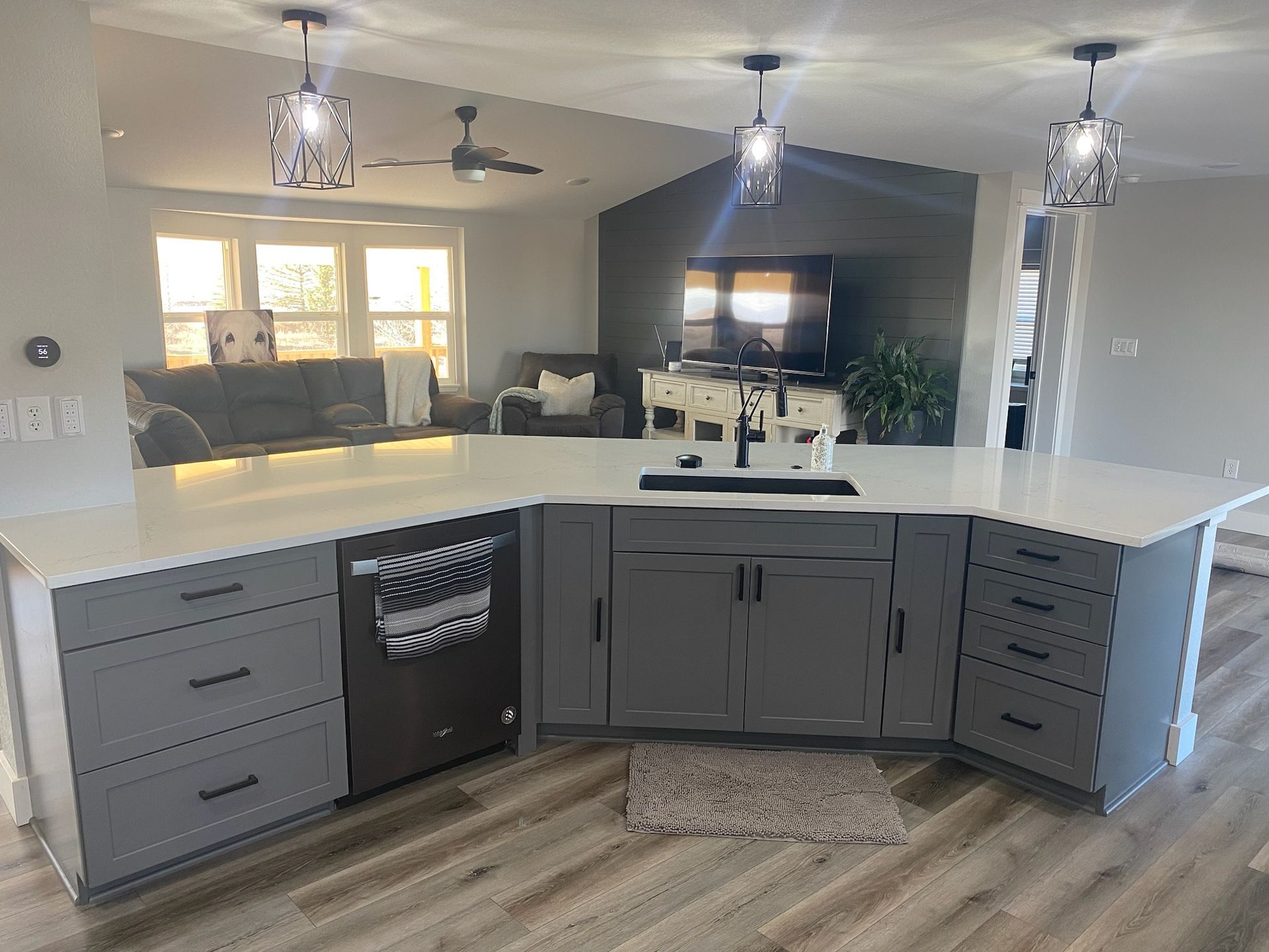 A kitchen with gray cabinets and white counter tops in a mobile home.