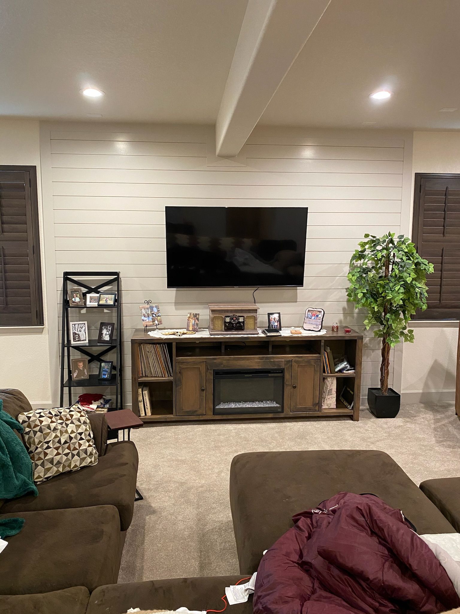 A living room with a couch , ottoman , fireplace and television.