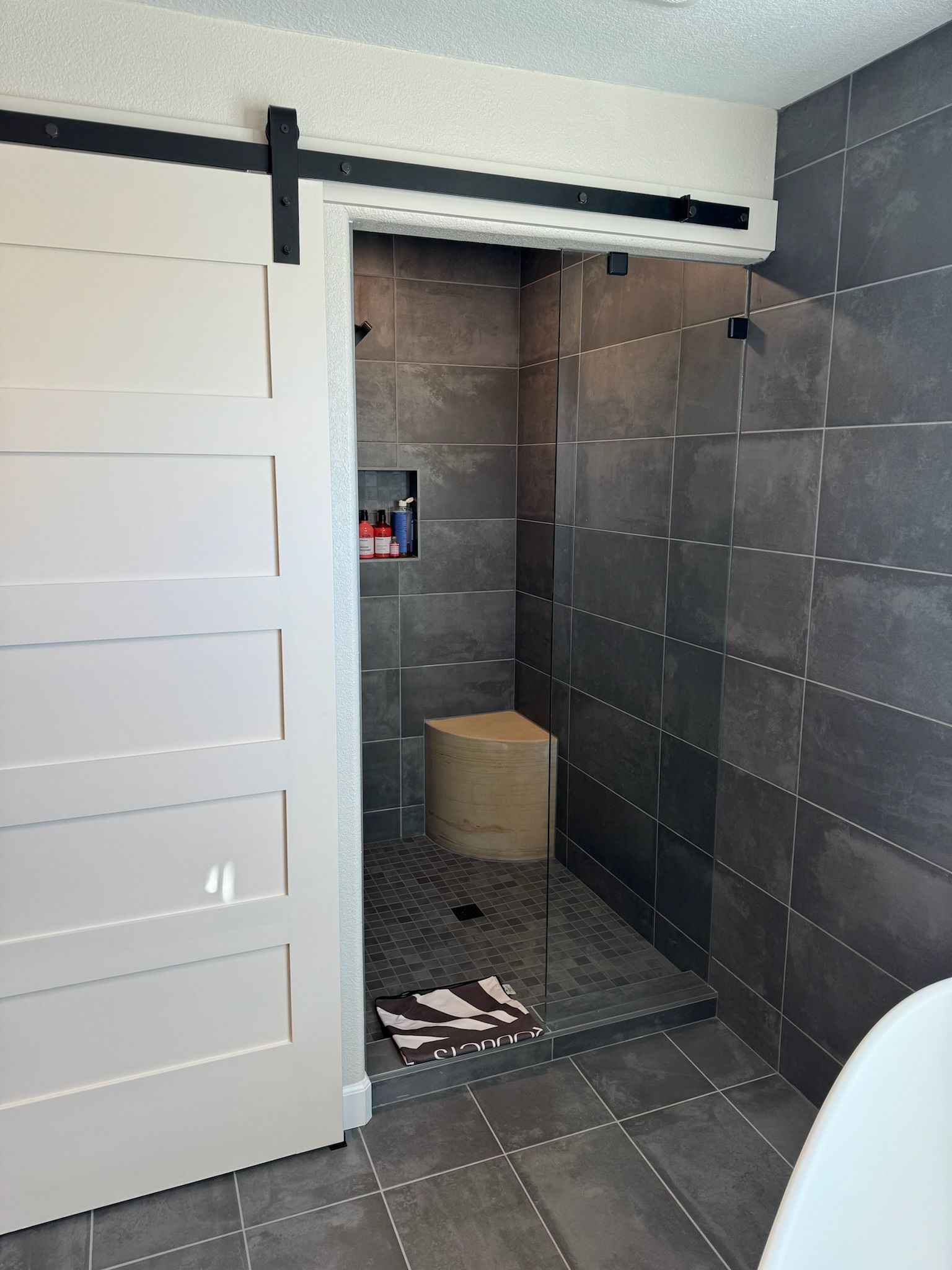 A bathroom with a sliding barn door leading to a shower