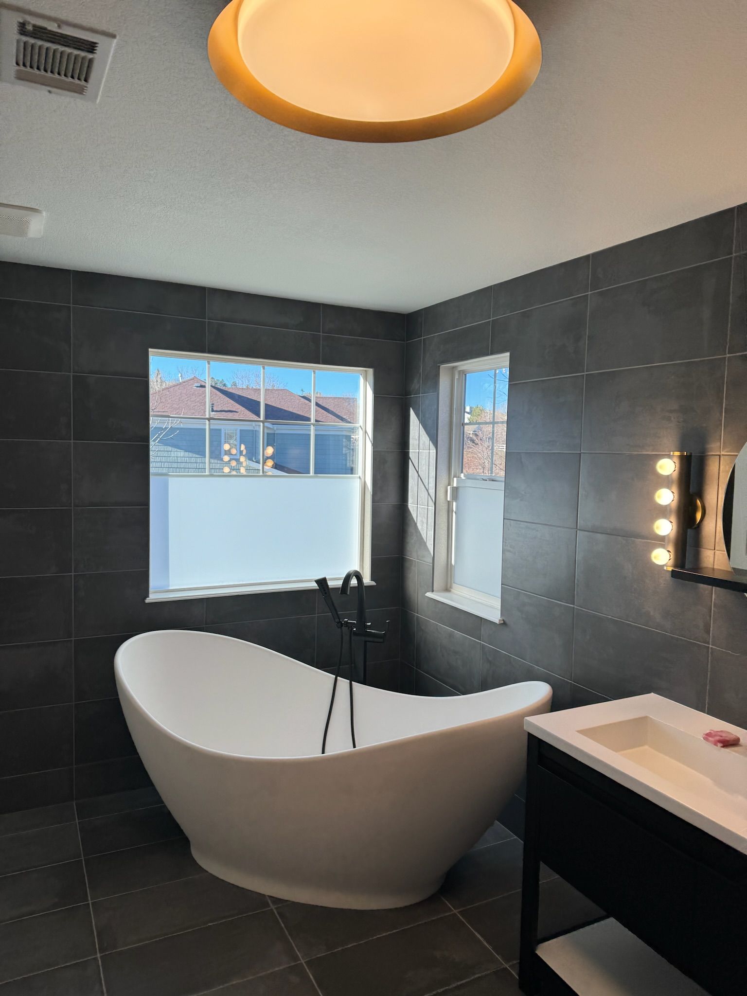 A bathroom with a tub , sink , mirror and window