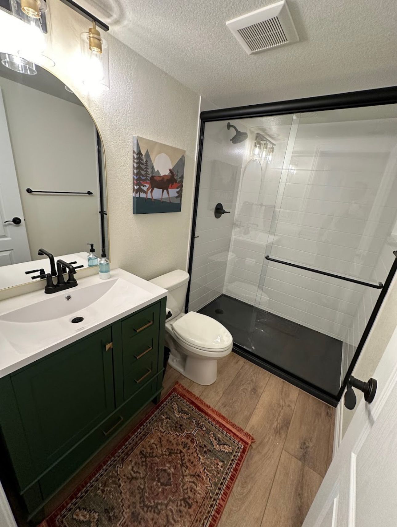 A bathroom with a toilet , sink , mirror and shower.