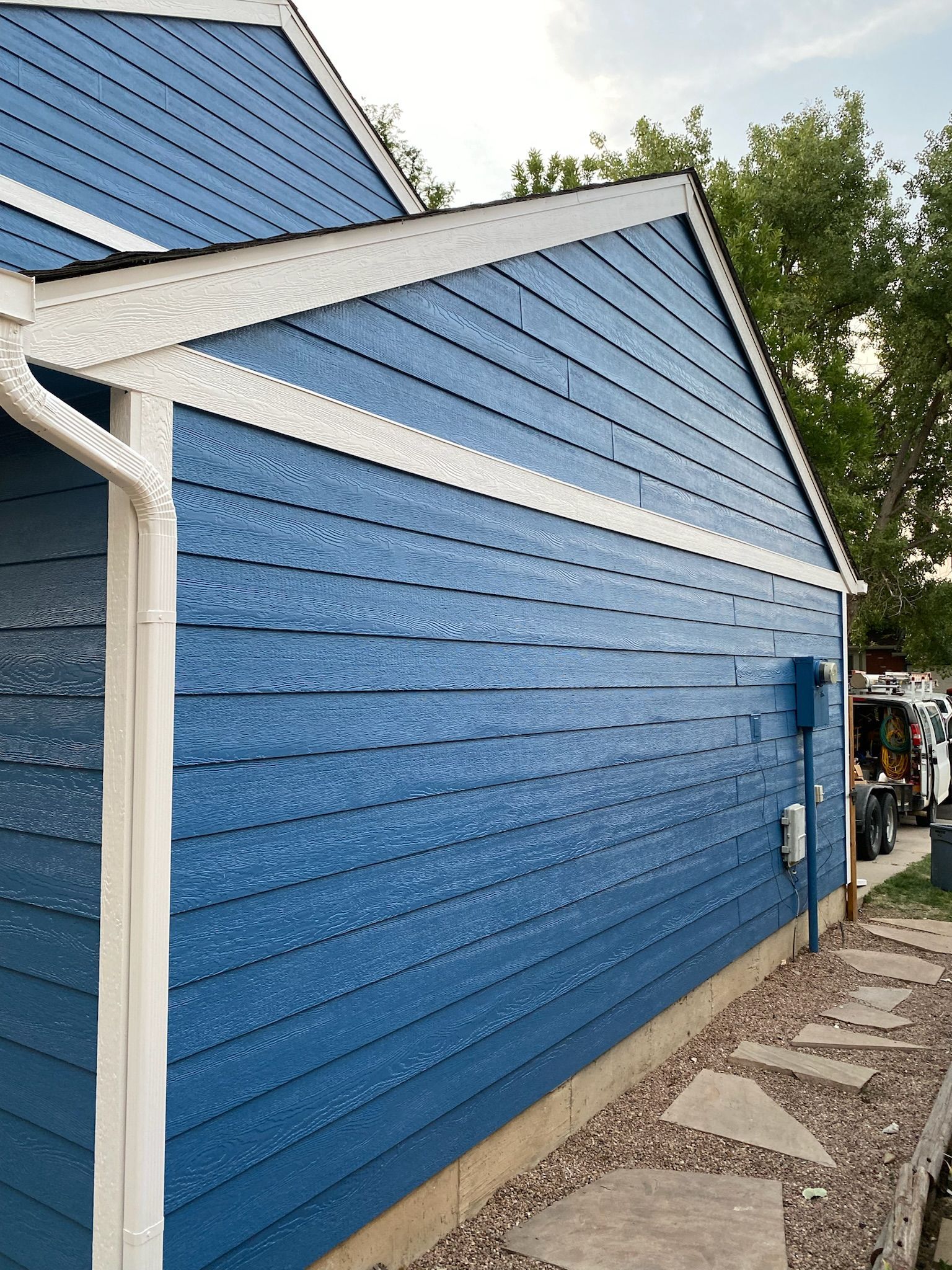 The side of a blue house with white trim and gutters.