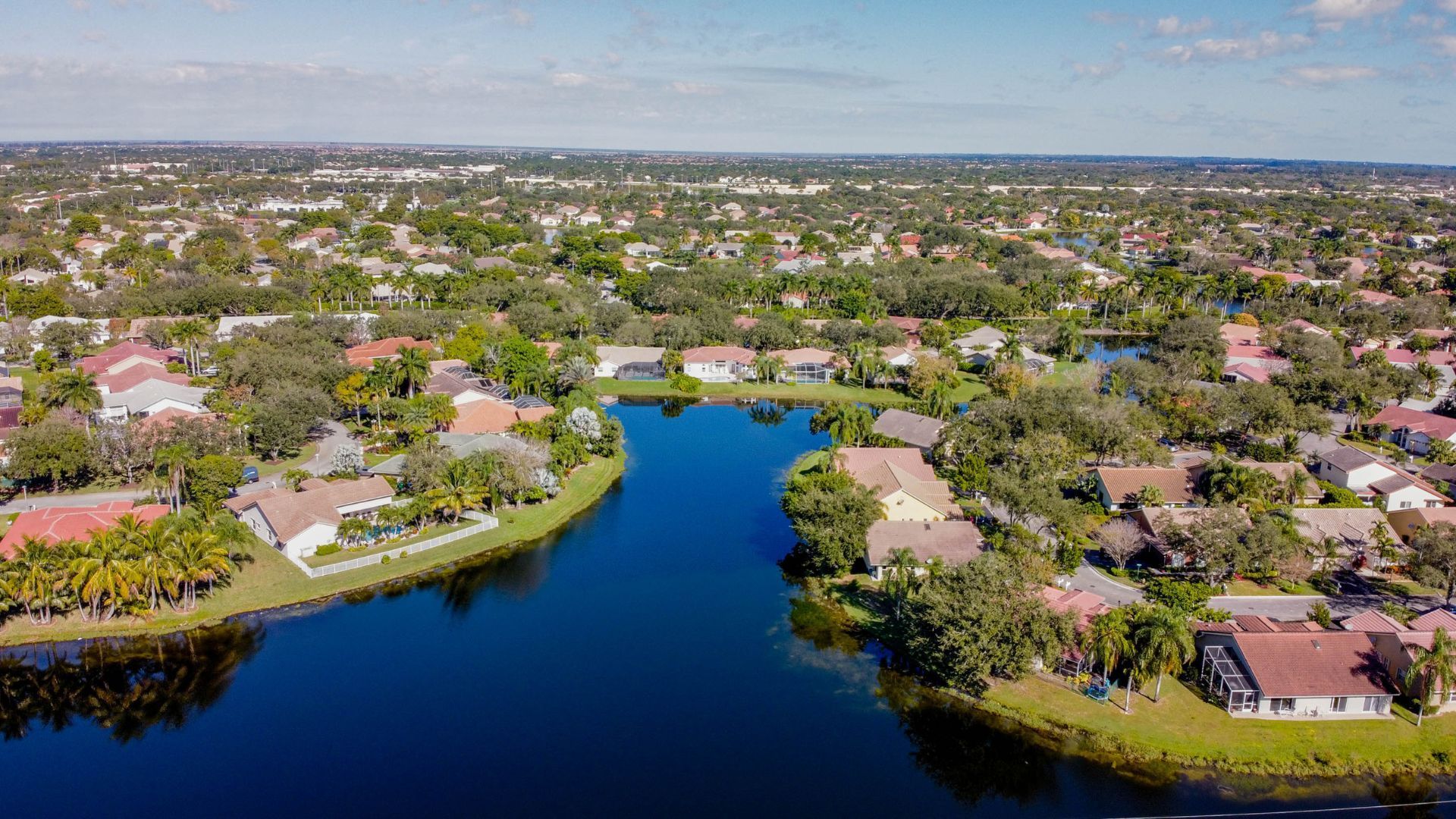 An aerial view of a residential area surrounded by trees and a lake.