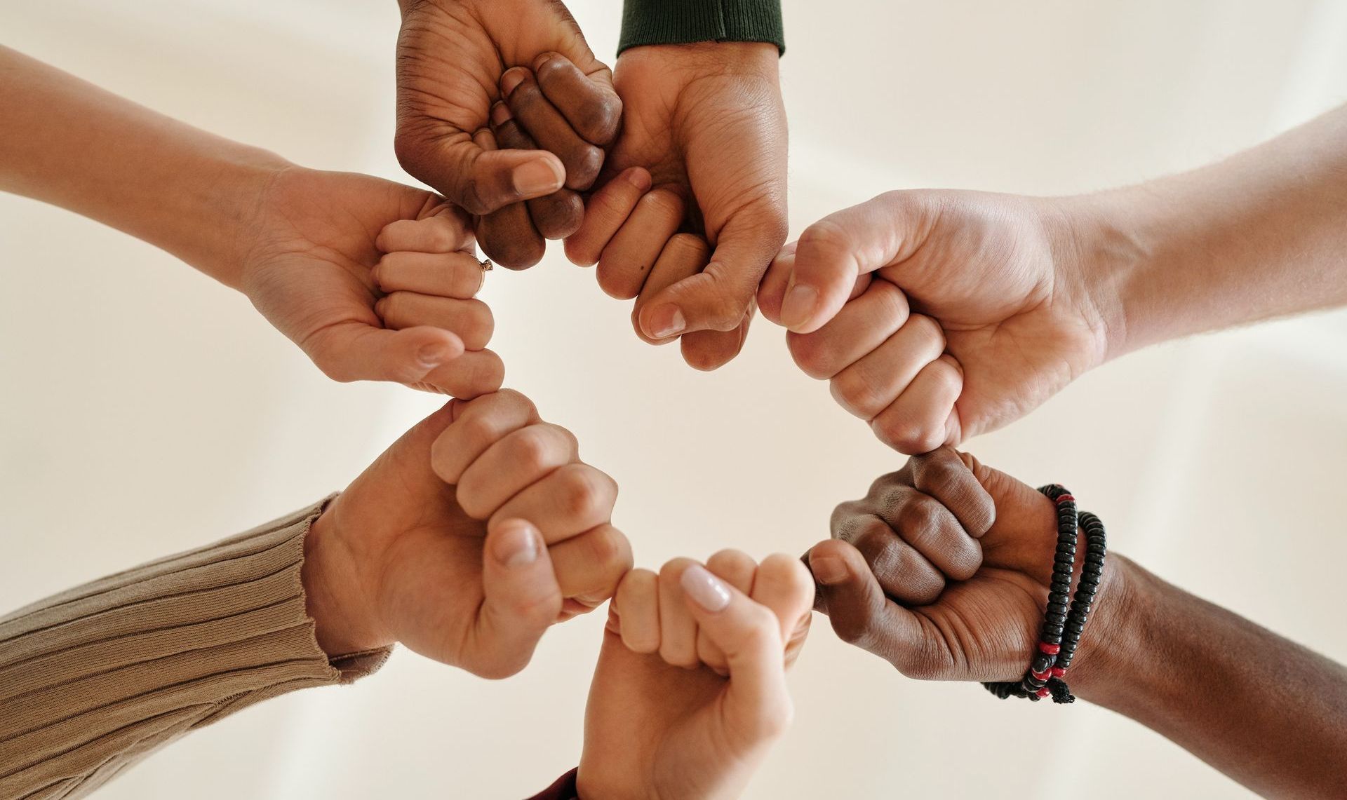 Hands of diverse people in a circle, fists touching, symbolizing unity and teamwork.