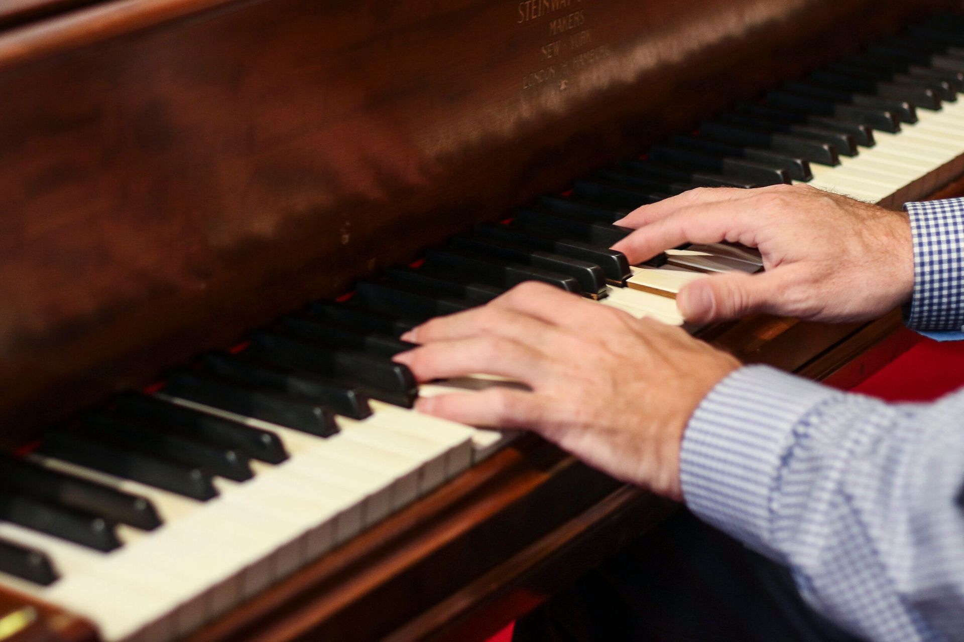 Hands playing a brown piano; close-up shot.