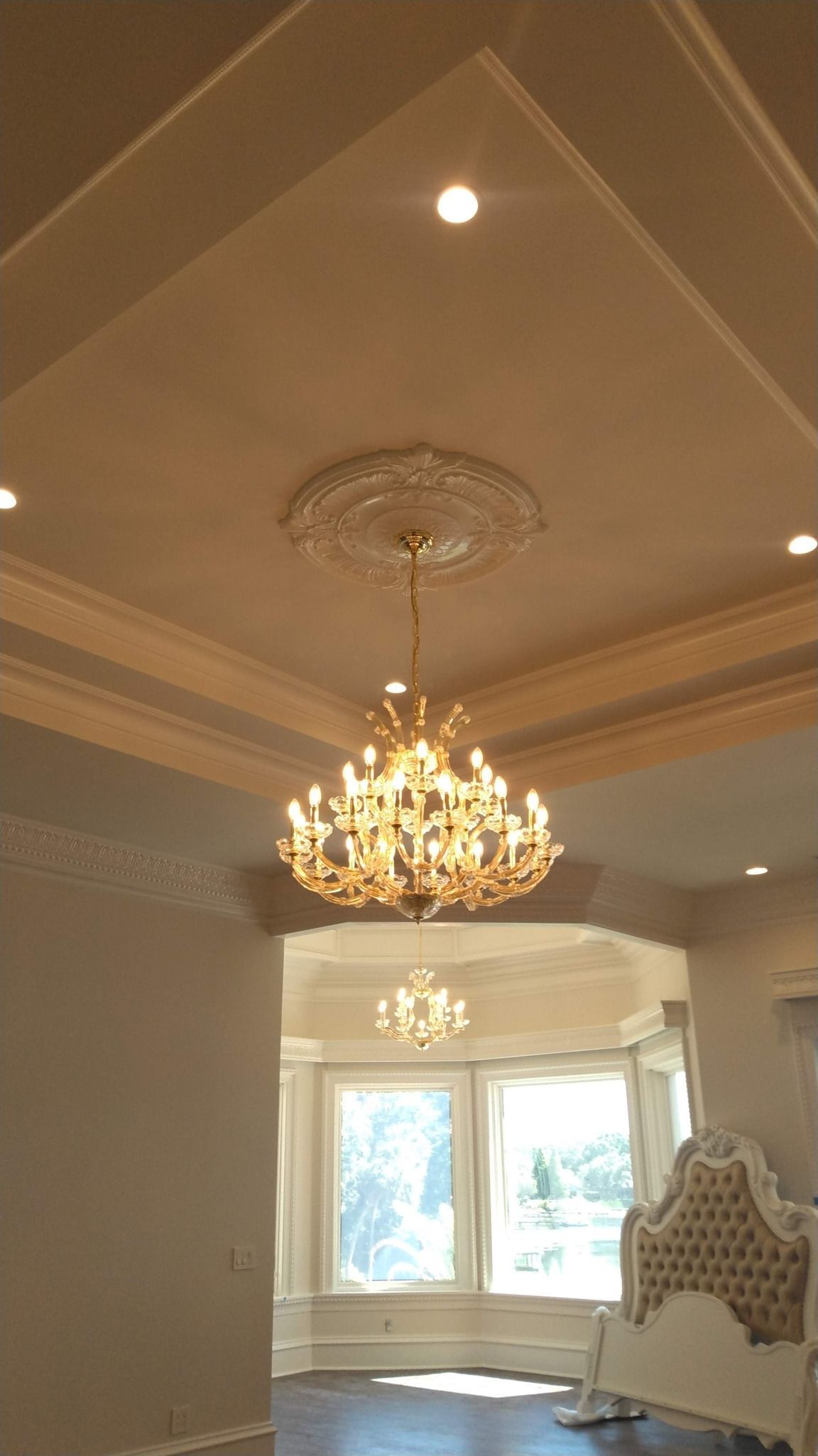 Ornate chandelier hangs in a room with a coffered ceiling.