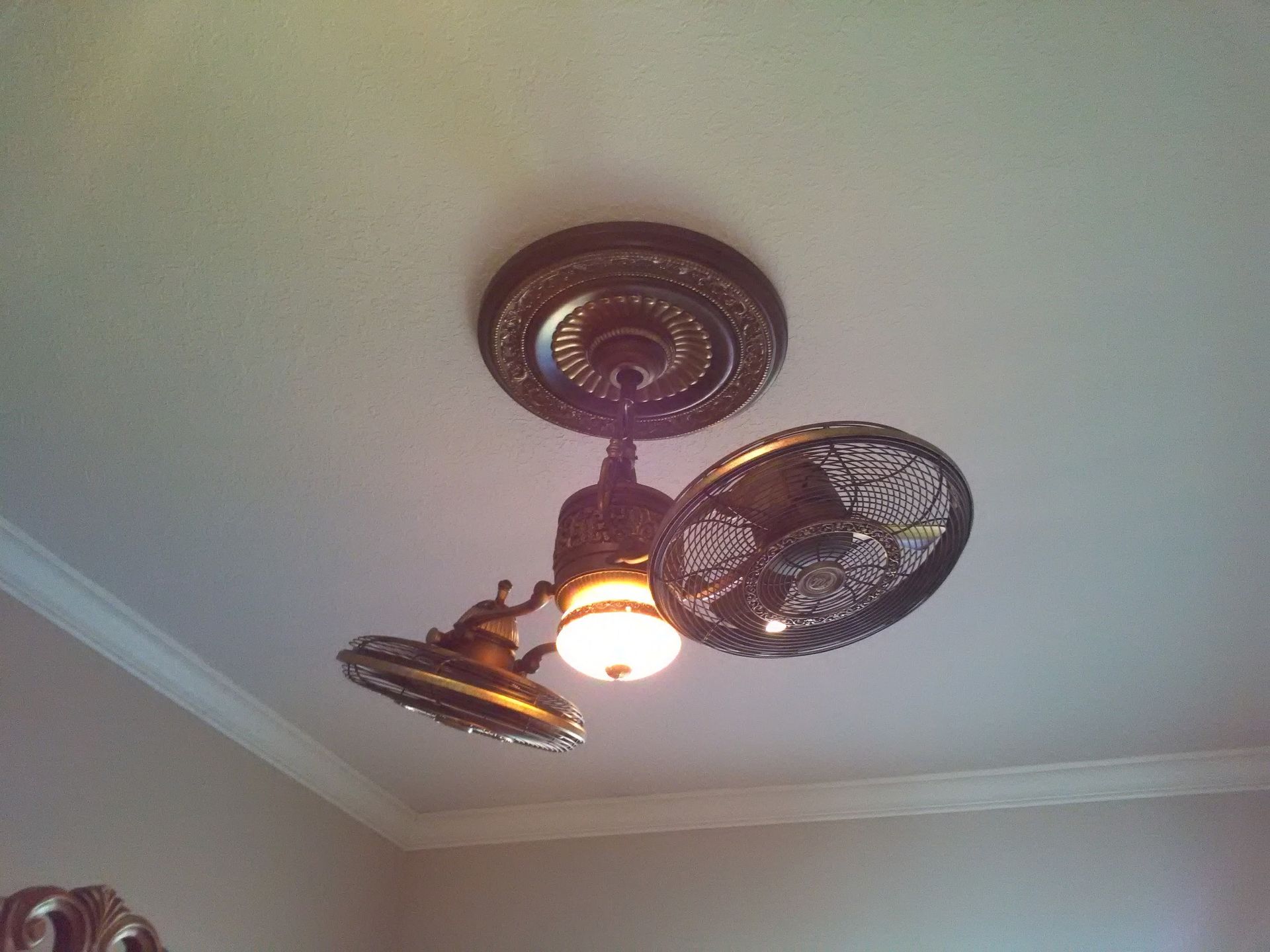 Antique bronze ceiling fan with ornate detailing, light fixture, against a white ceiling.