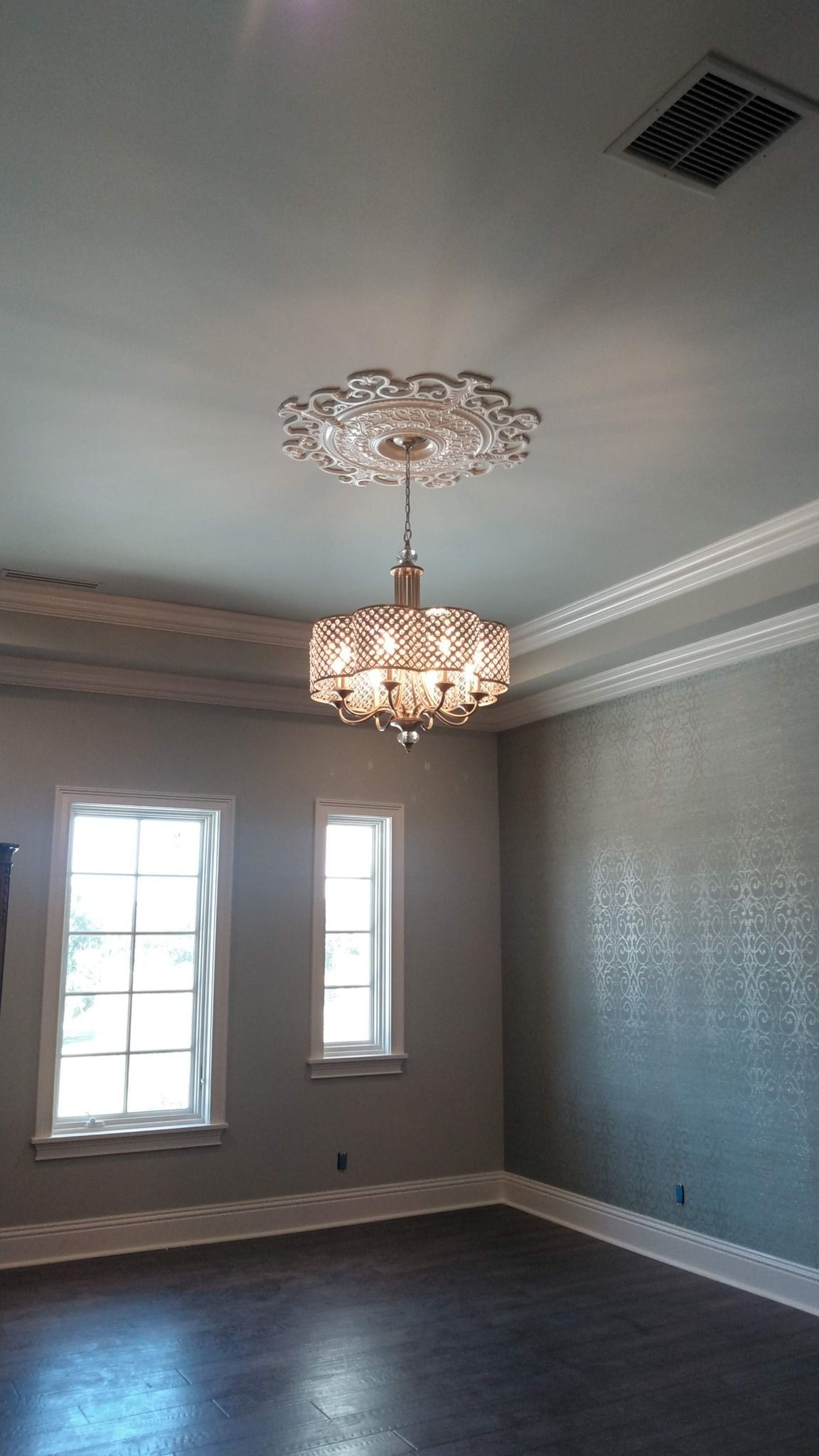 Elegant room with chandelier, windows, and patterned wallpaper.