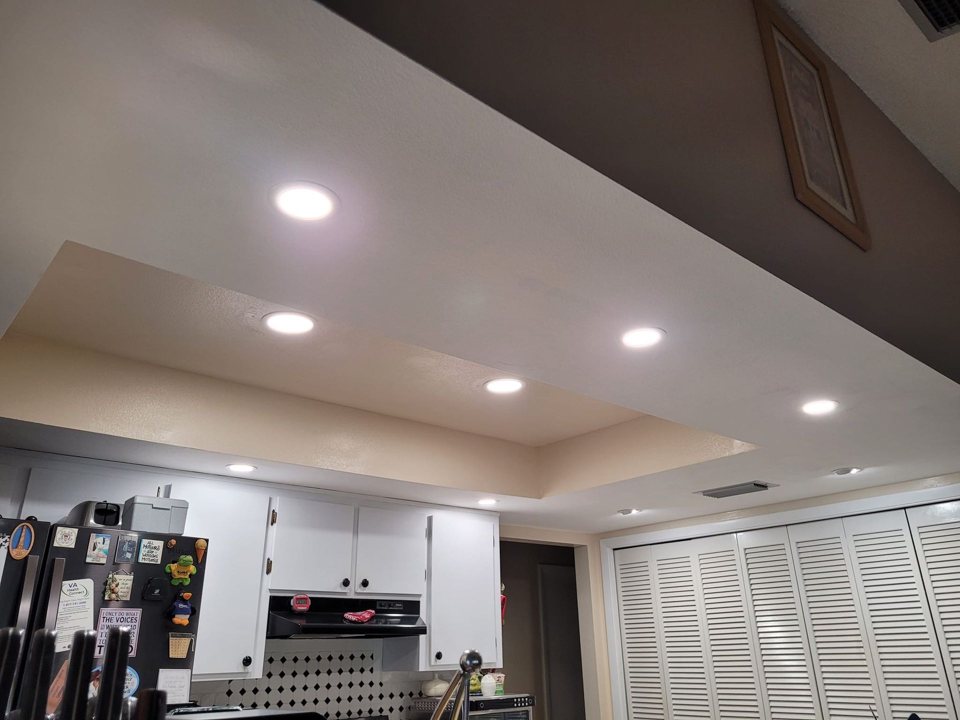 Kitchen ceiling with recessed lighting. White cabinets and shutters below.