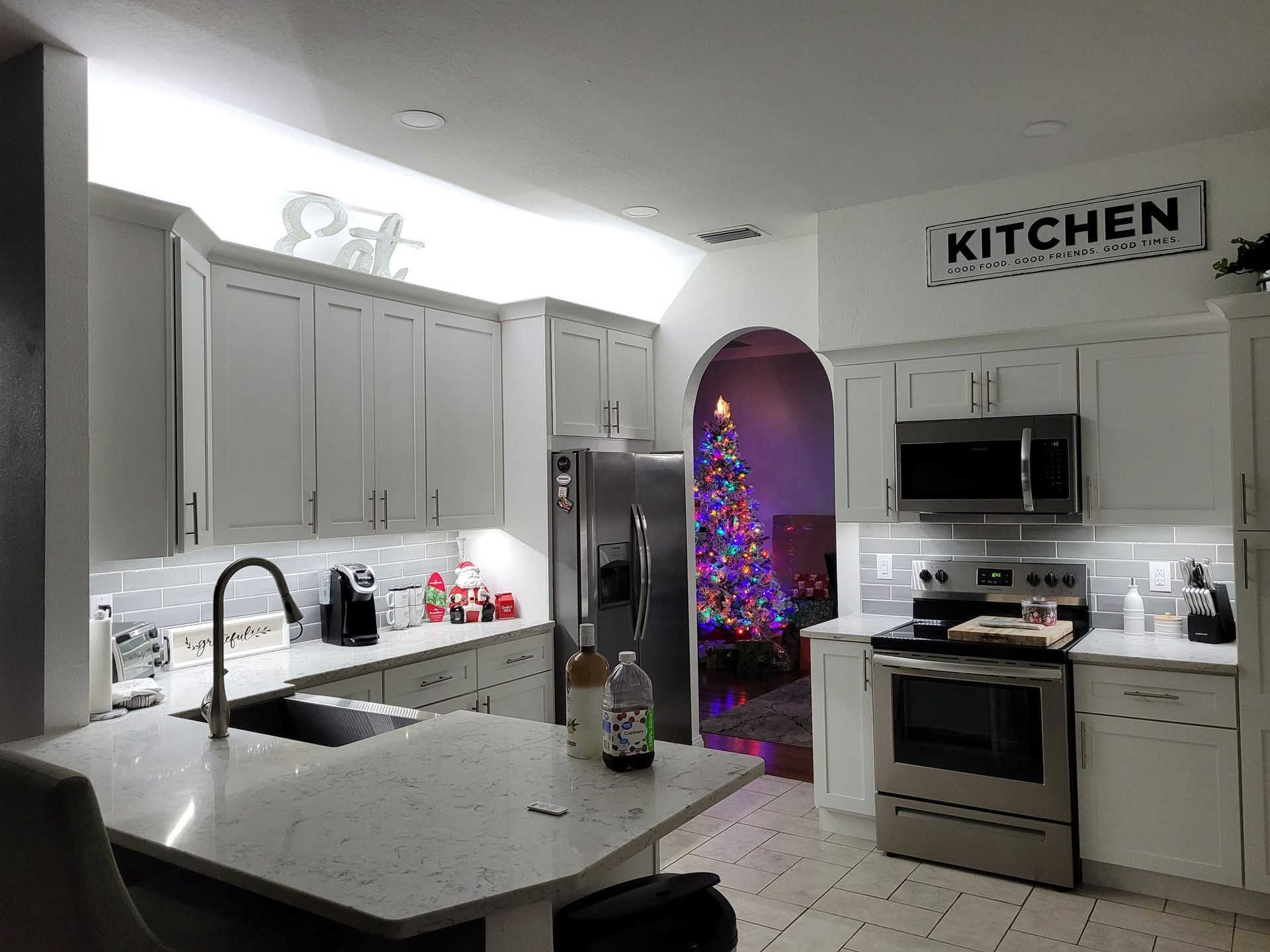 White kitchen with cabinets, stainless steel appliances, and a Christmas tree visible in the doorway.
