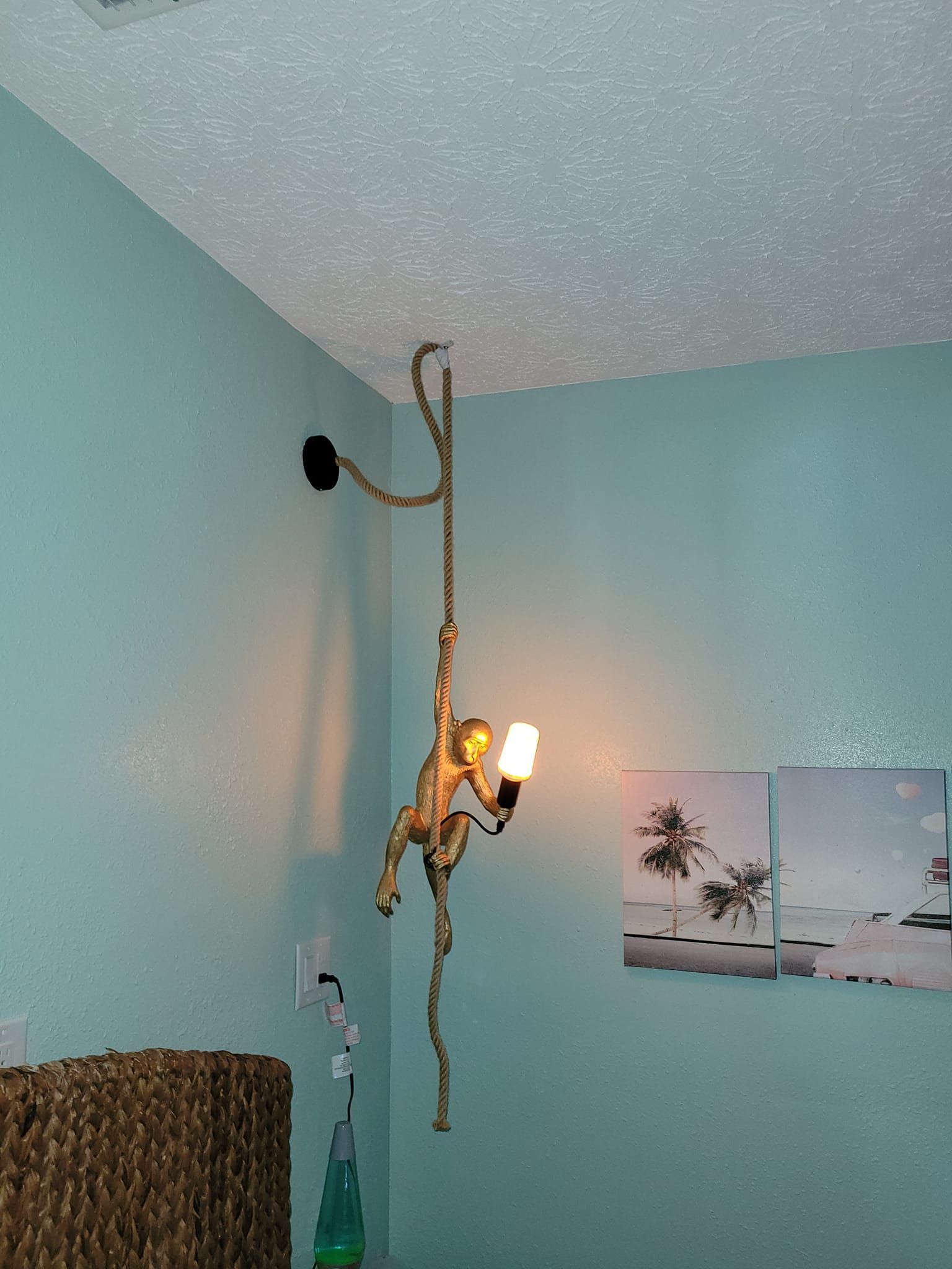 A gold monkey-shaped light fixture hangs from a white ceiling, casting warm light in a room with blue walls.