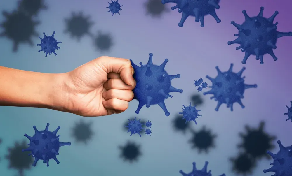 A person is holding a fist in front of a bunch of bacteria.