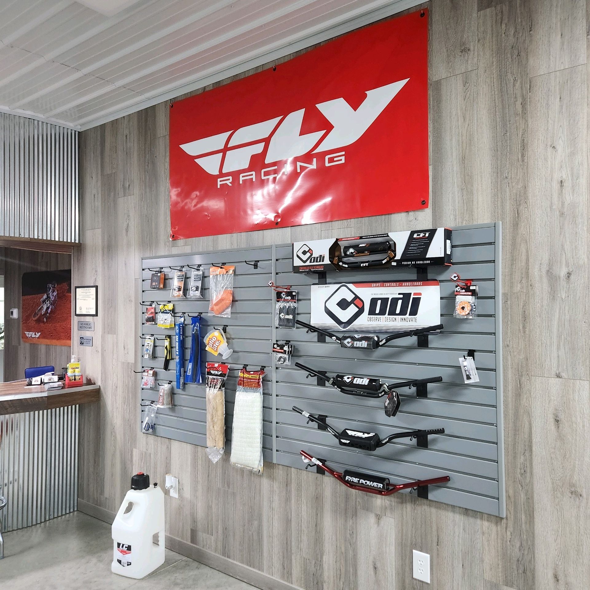 Motorcycle parts and accessories displayed on a retail wall, under a red and white 