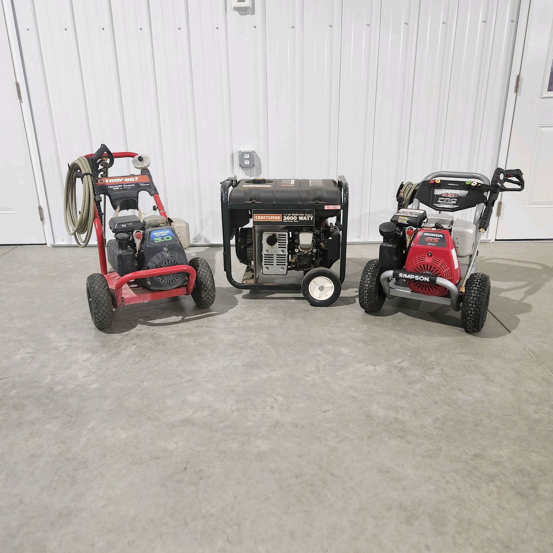 Two pressure washers and a generator on a concrete floor.
