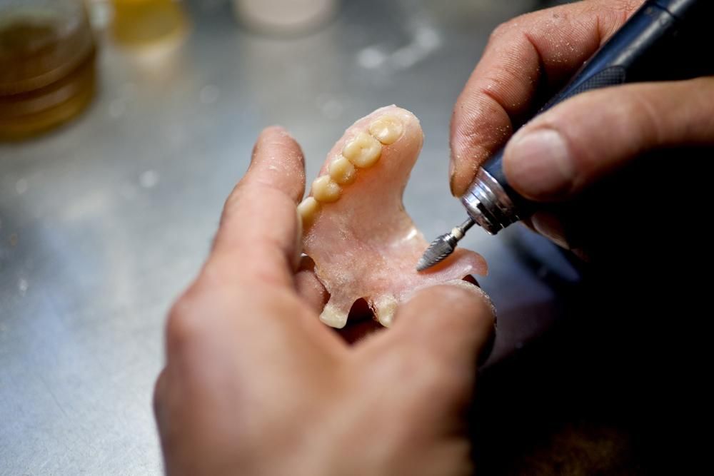 A Person Is Working on A Denture with A Machine — Peter McLennan Denture Clinic in Grafton, NSW