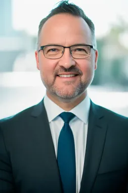 A man in a suit and tie is smiling for the camera.