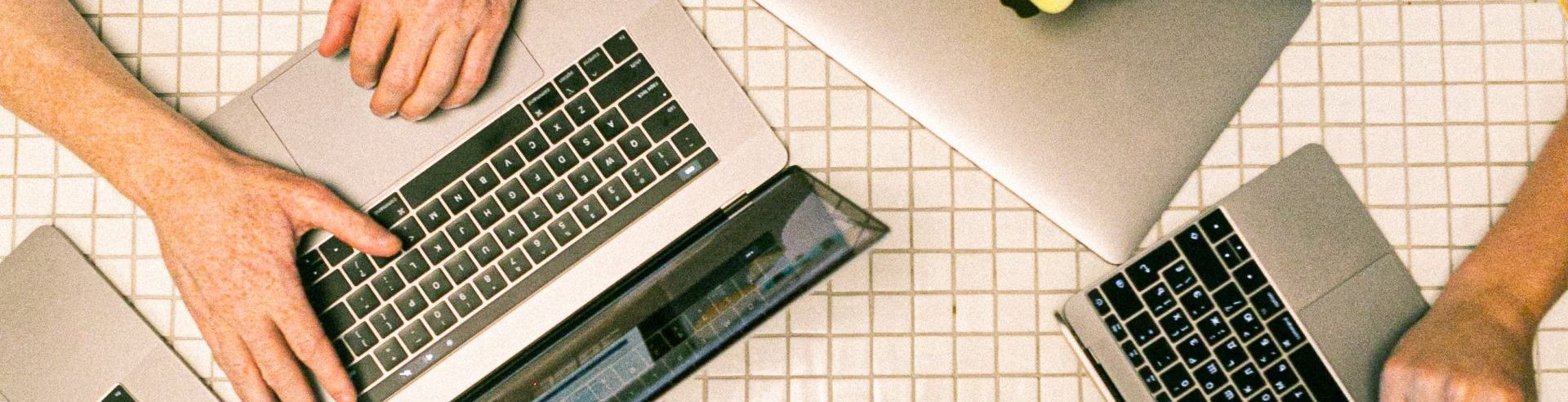 A group of people are sitting at a table using laptops.