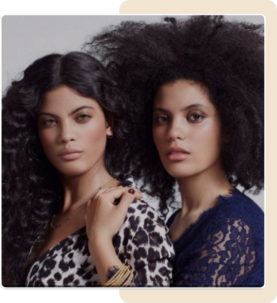 Two women with curly hair are posing for a picture