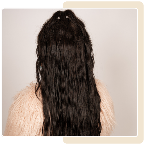 A woman with long black hair is wearing a fur coat.
