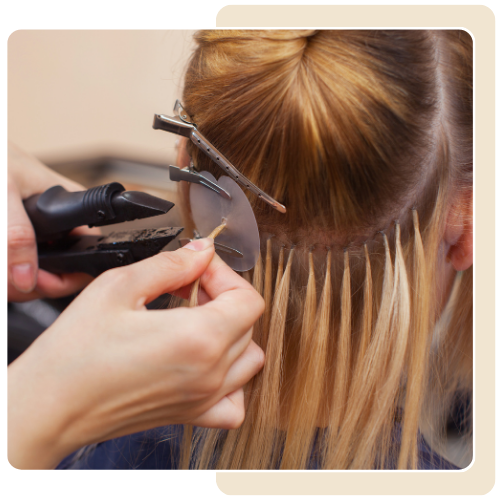 A woman is getting her hair extensions done by a hairdresser