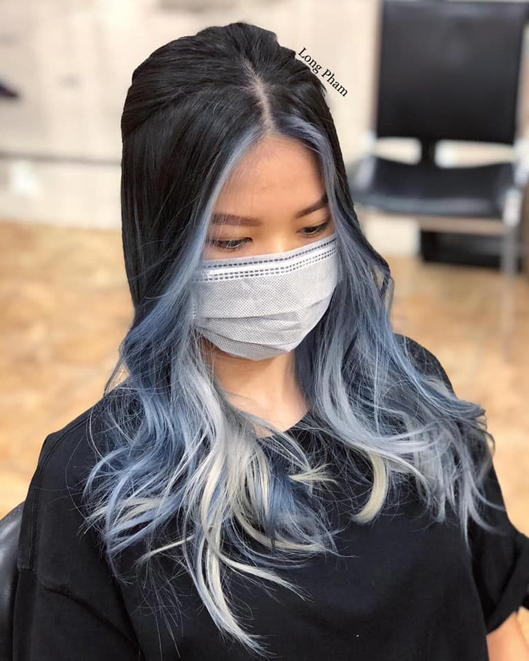 a woman with long black hair and blue highlights is wearing a mask .