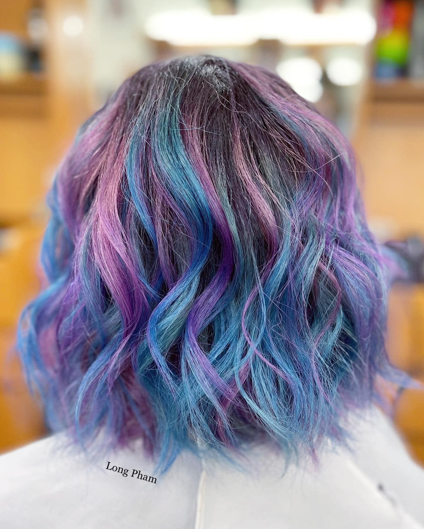 a woman with blue and purple hair is sitting in a chair .