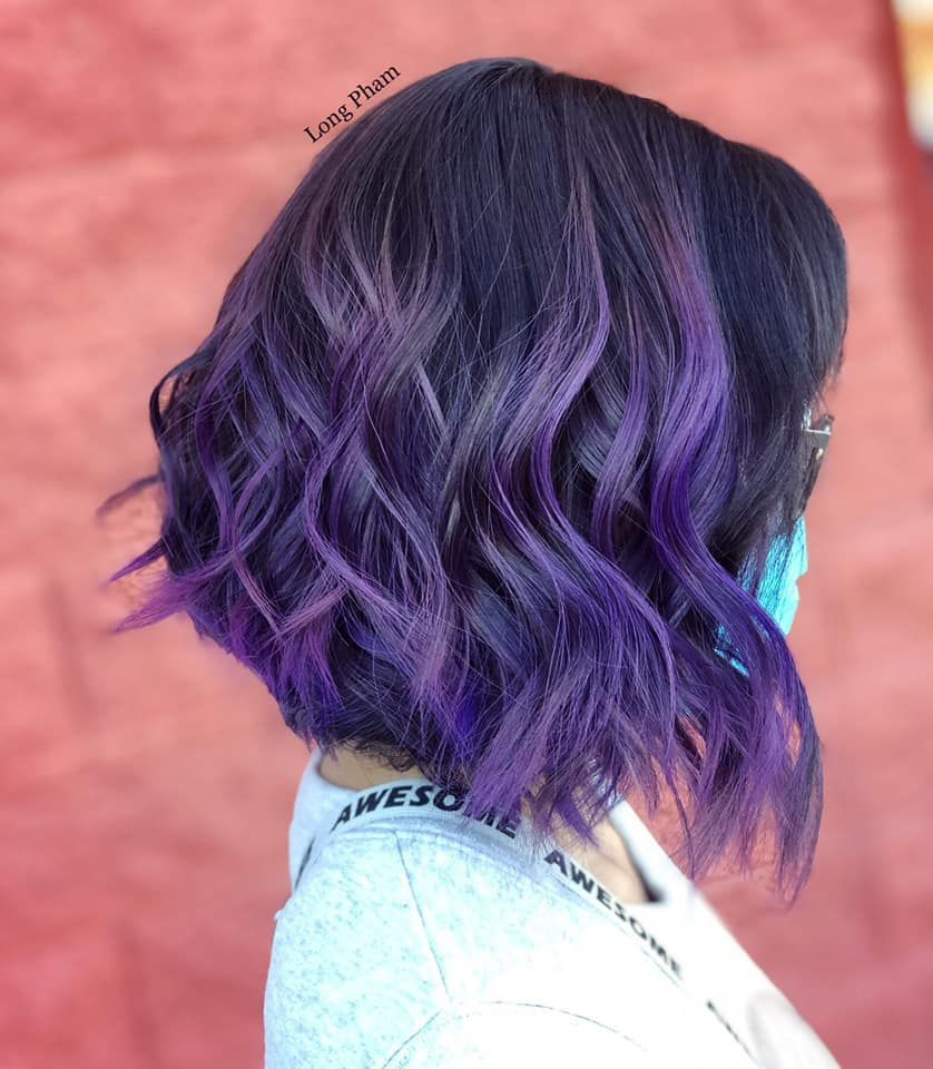 a woman with purple hair is wearing a mask .