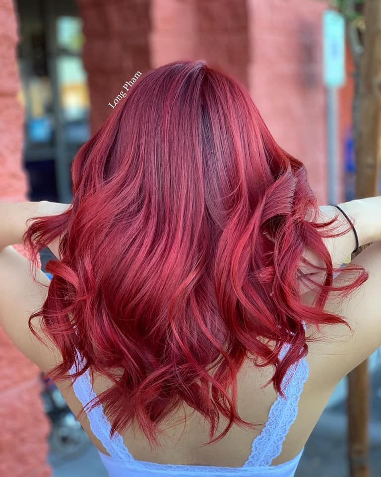 a woman with red hair is wearing a blue tank top .