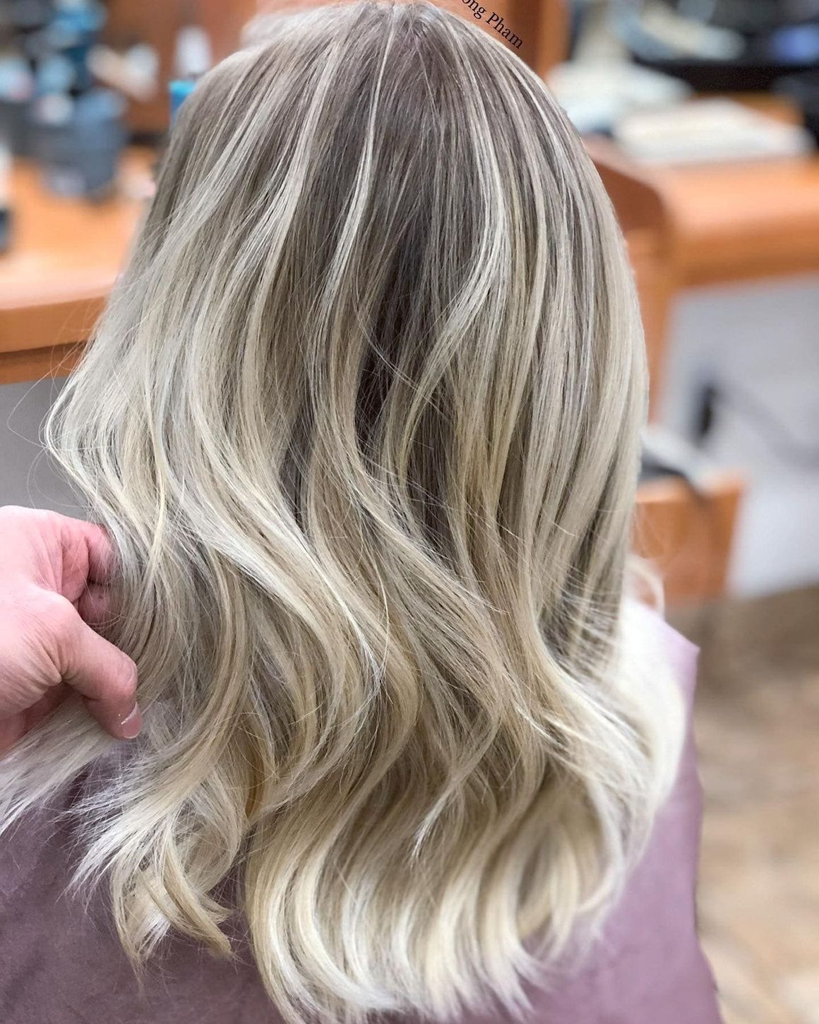a woman with long blonde hair is getting her hair cut by a hairdresser .