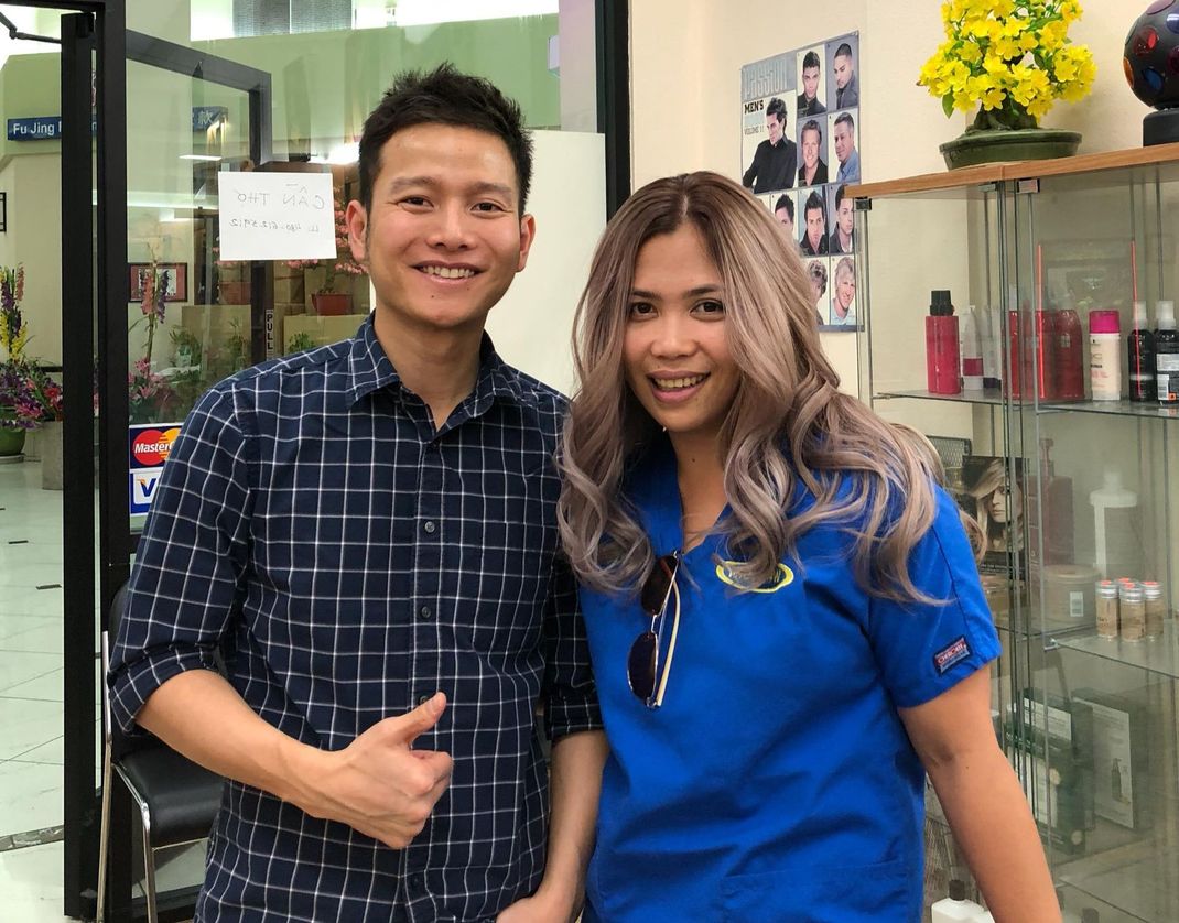 a man and a woman are posing for a picture in a hair salon .