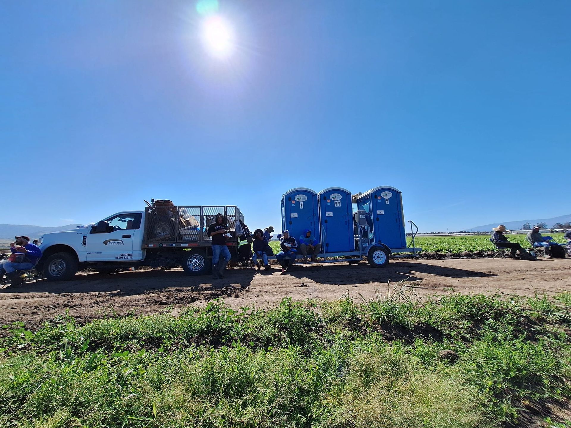 A truck is pulling a trailer with portable toilets on it.