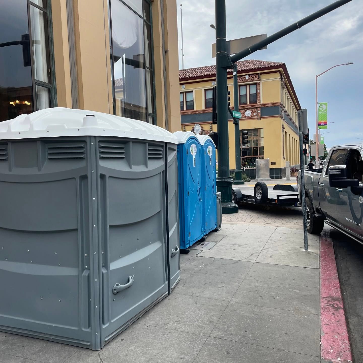 Two portable toilets are parked on the side of the road