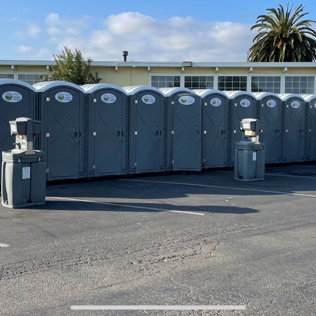 A row of portable toilets are lined up in a parking lot