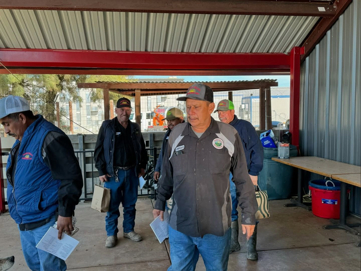 A group of men are standing under a covered area.