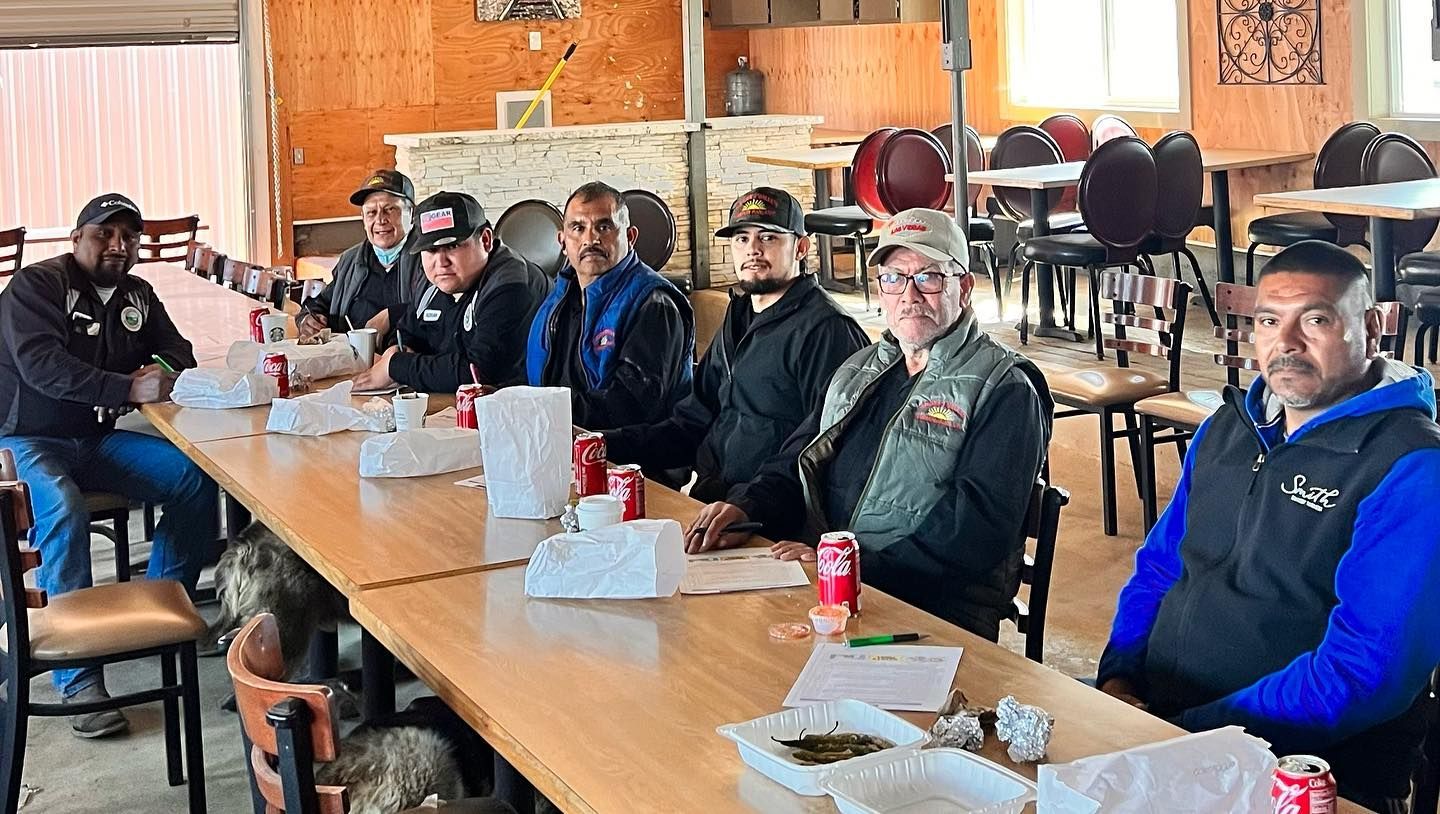 A group of men are sitting at a long table in a restaurant.