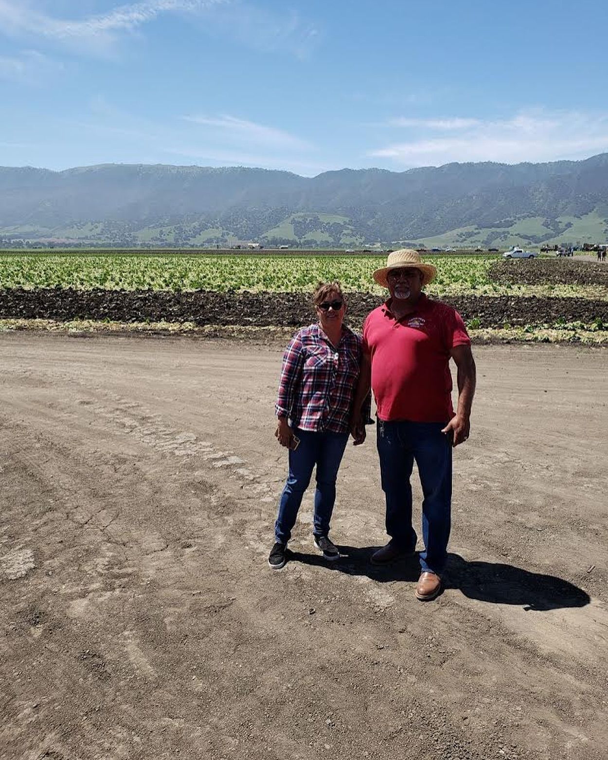 A man and a woman are standing next to each other in a dirt field.