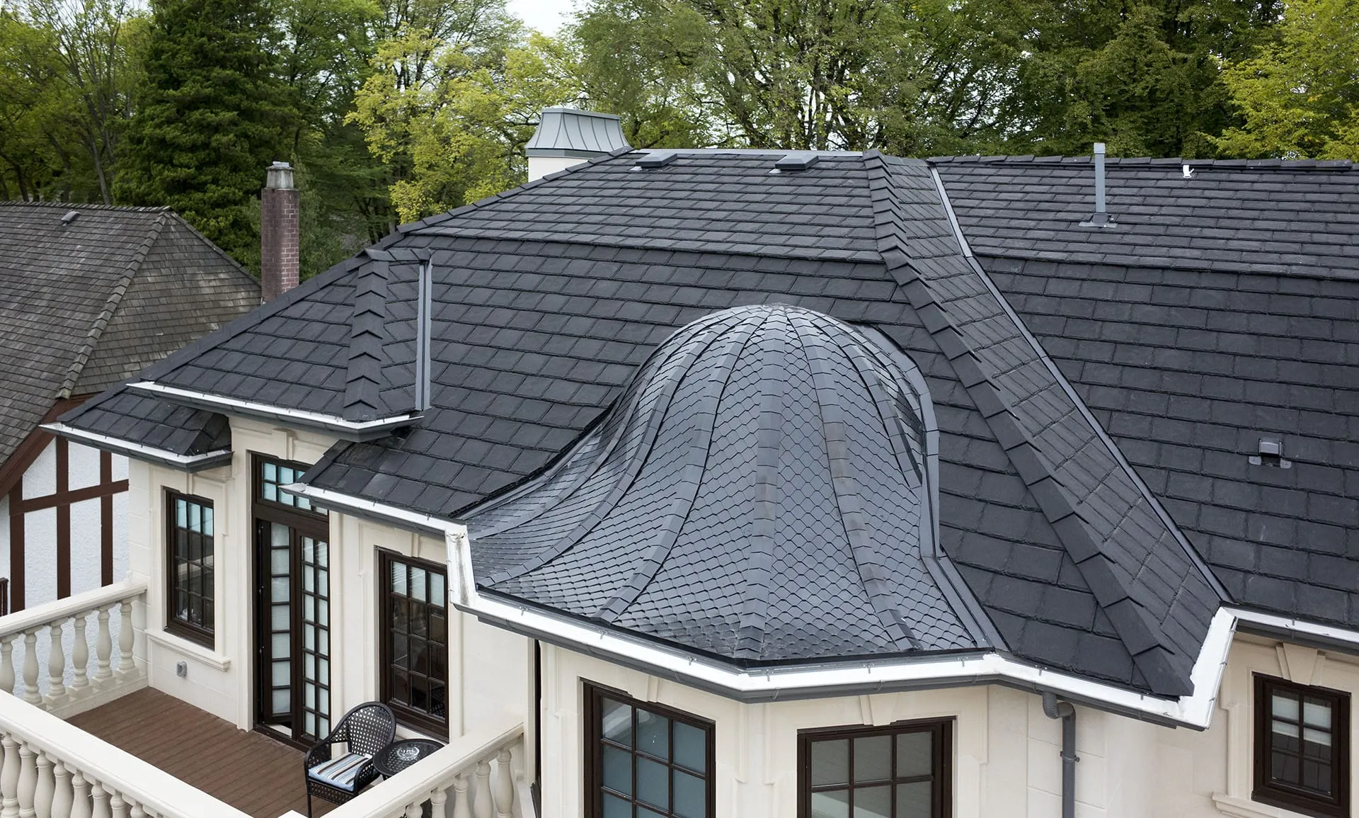 A white house with a black roof and a balcony