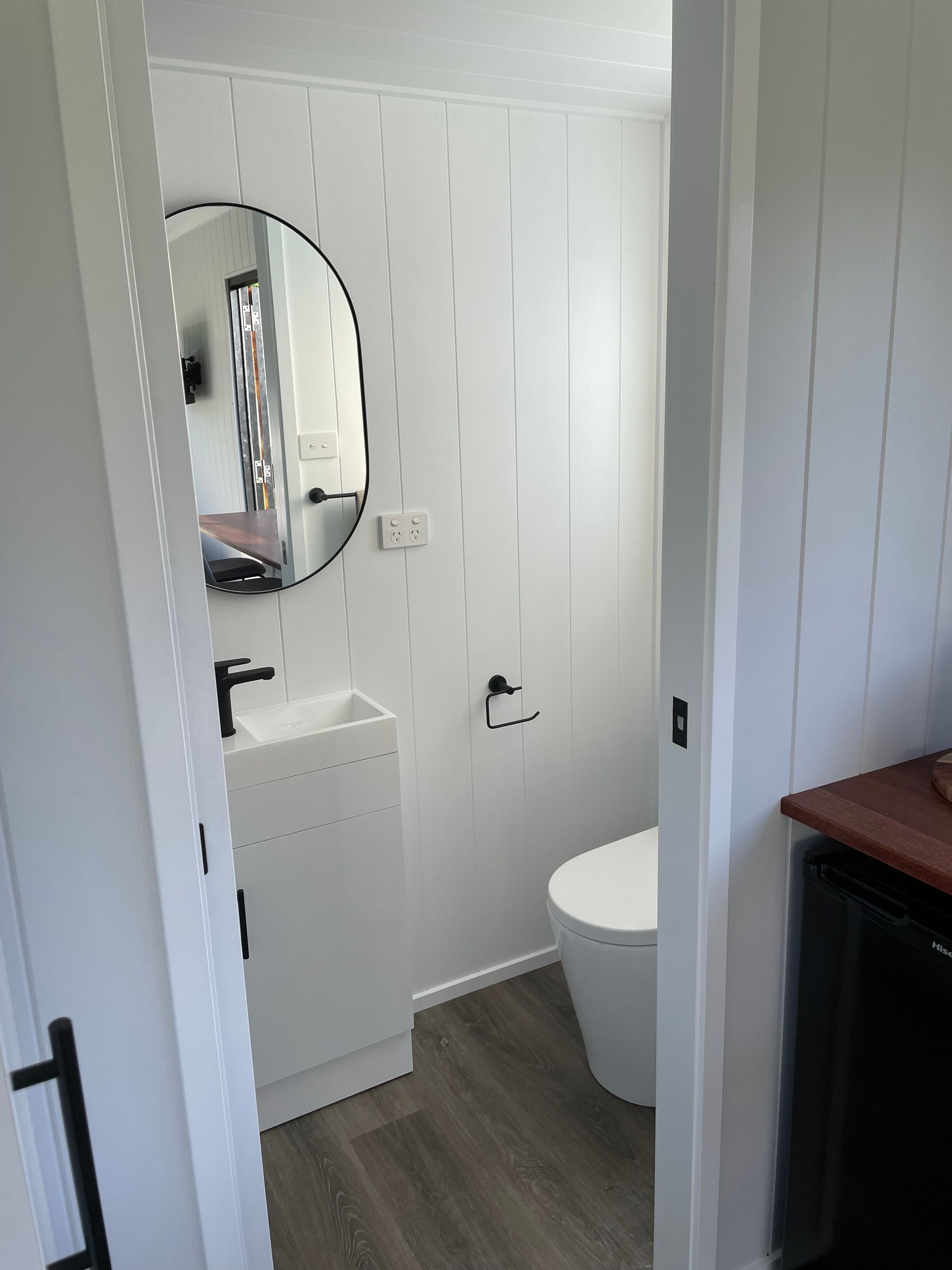 Small white bathroom with a toilet, sink, and black accents.