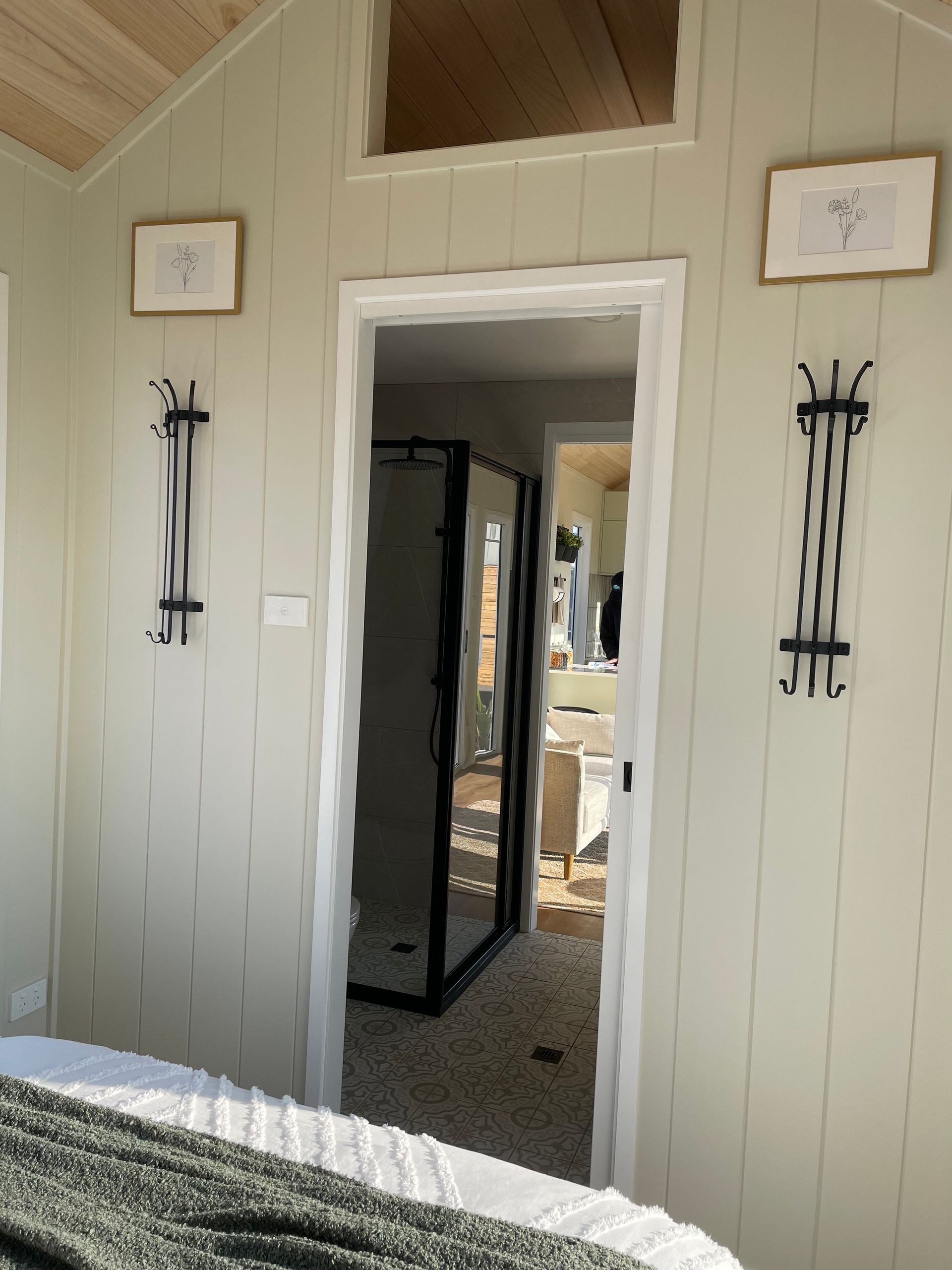 Bedroom interior with open doorway to bathroom, light green walls, decorative sconces, and framed artwork.