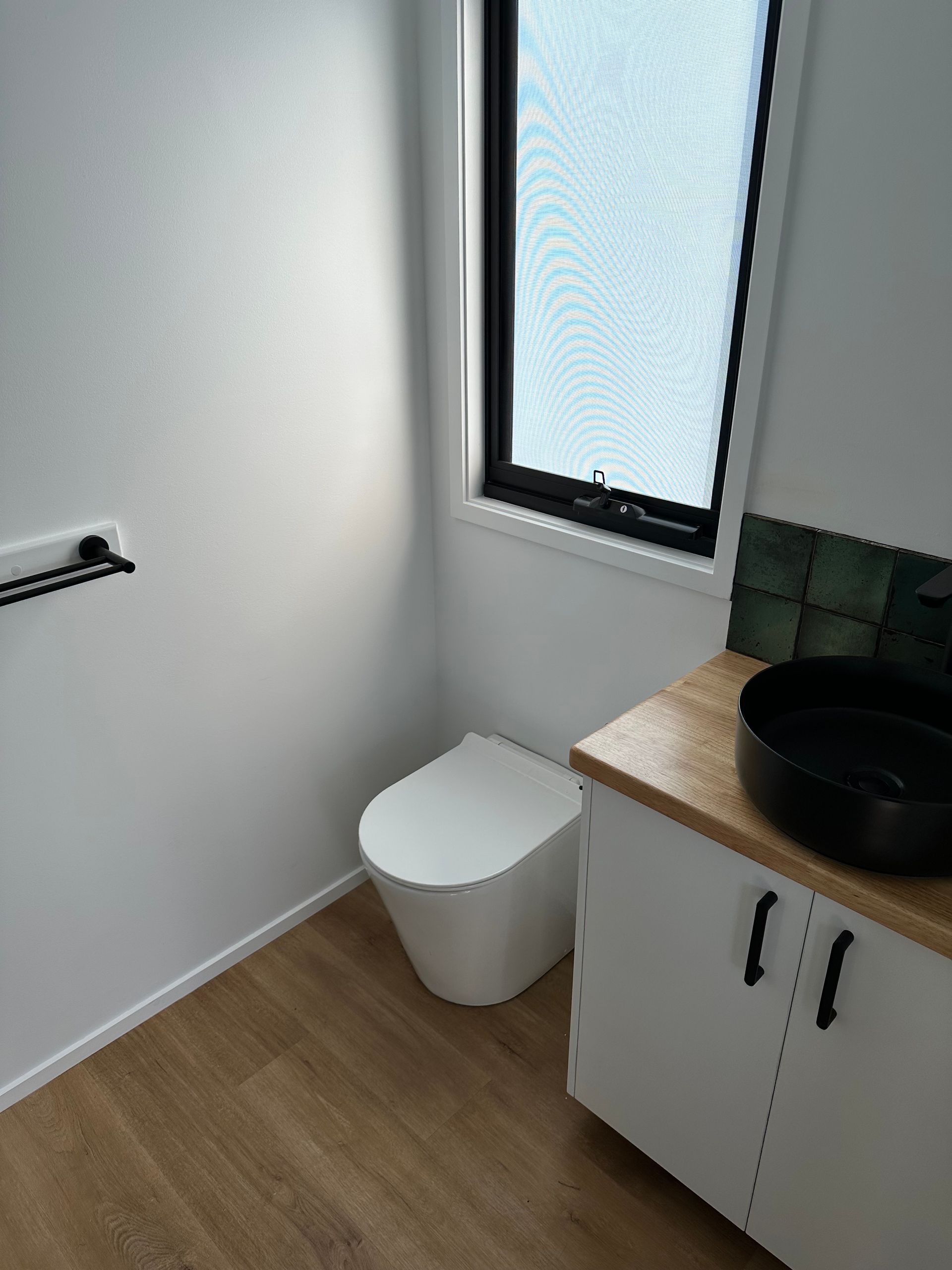Small modern bathroom with white walls, toilet, and vanity, and black accents.