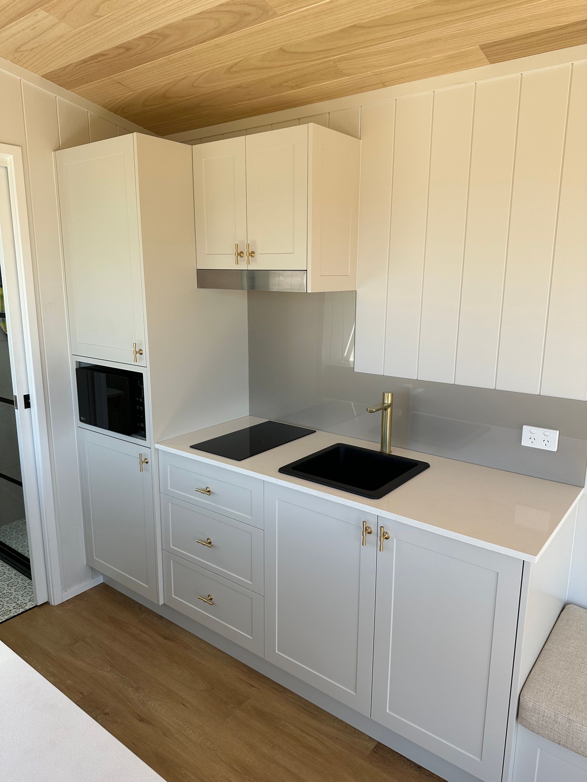 White kitchen with light countertops, cabinets, a microwave, and cooktop.