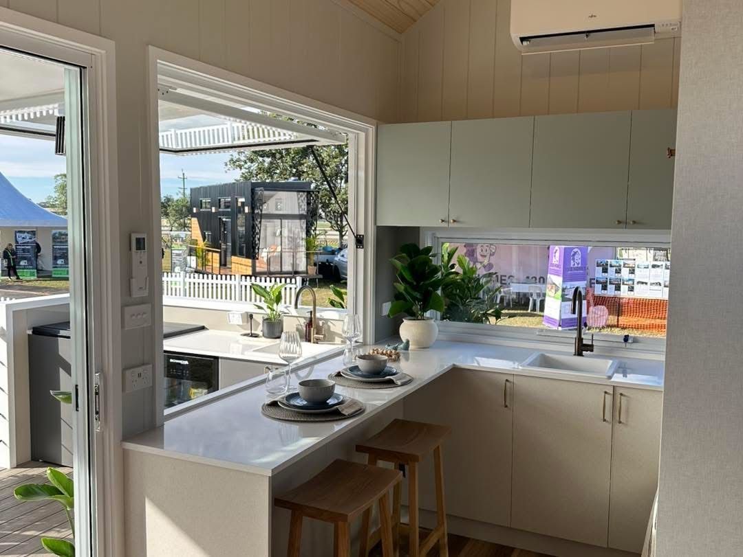 Interior view of a small kitchen with a countertop bar and open window overlooking an outdoor area.
