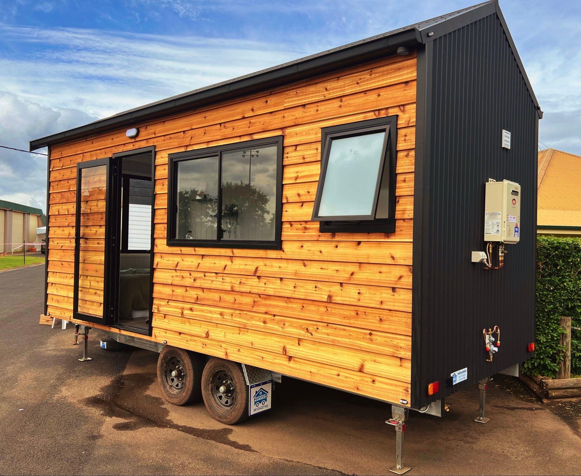 Tiny house on wheels with wood siding, black metal roof and accents.