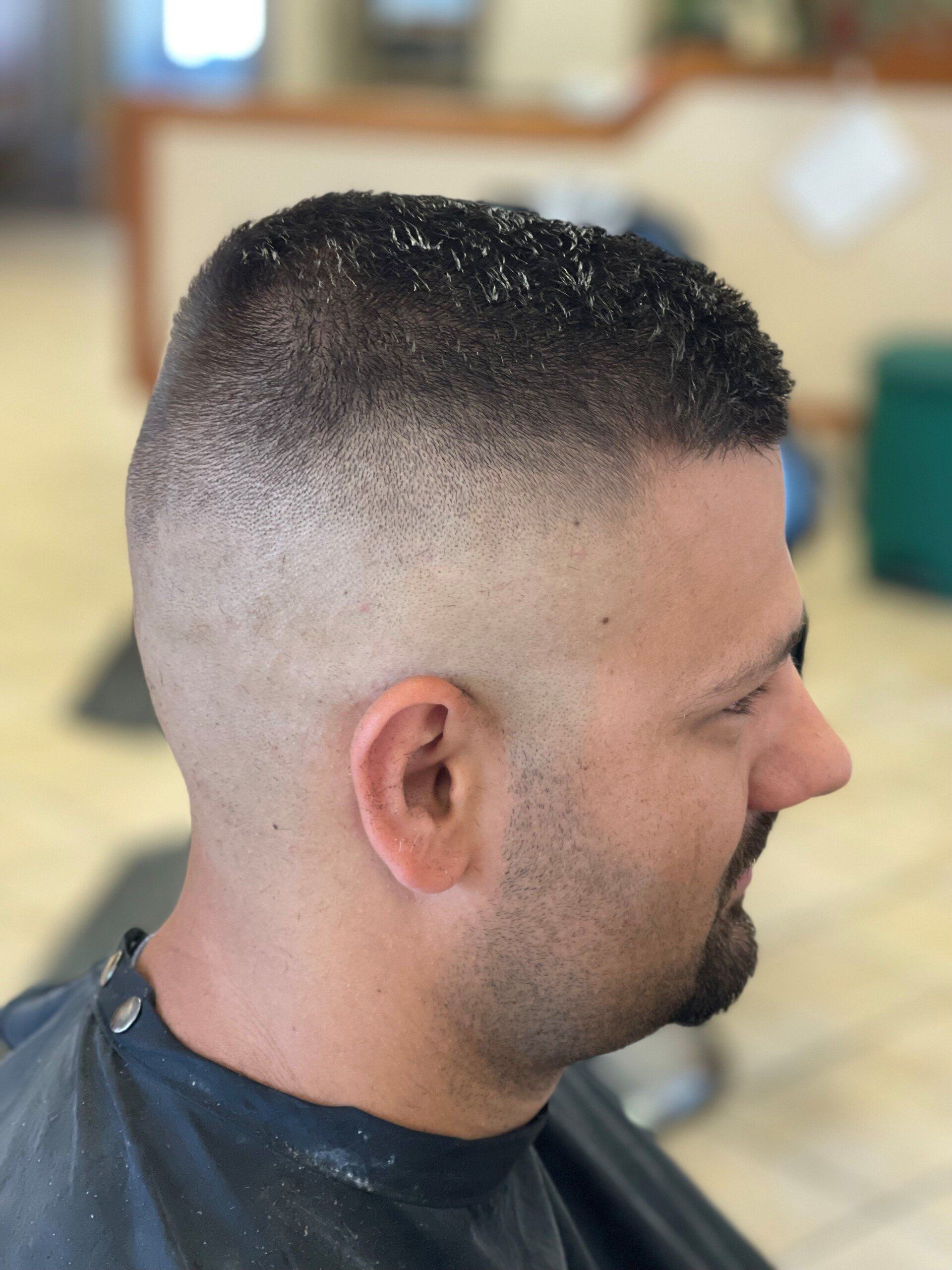 A man with a beard is getting his hair cut at a barber shop.