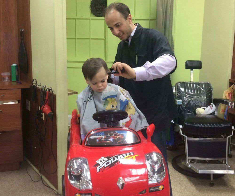 A little boy is getting his hair cut in a toy car