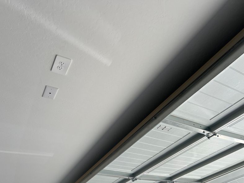 A close up of the ceiling of a garage with two electrical outlets.