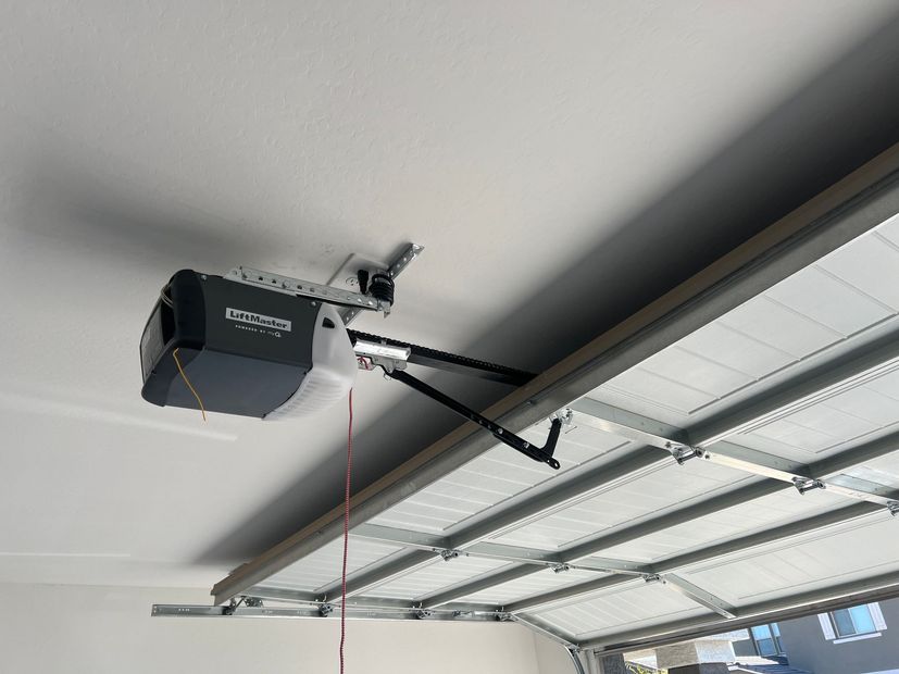 A garage door opener is hanging from the ceiling of a garage.