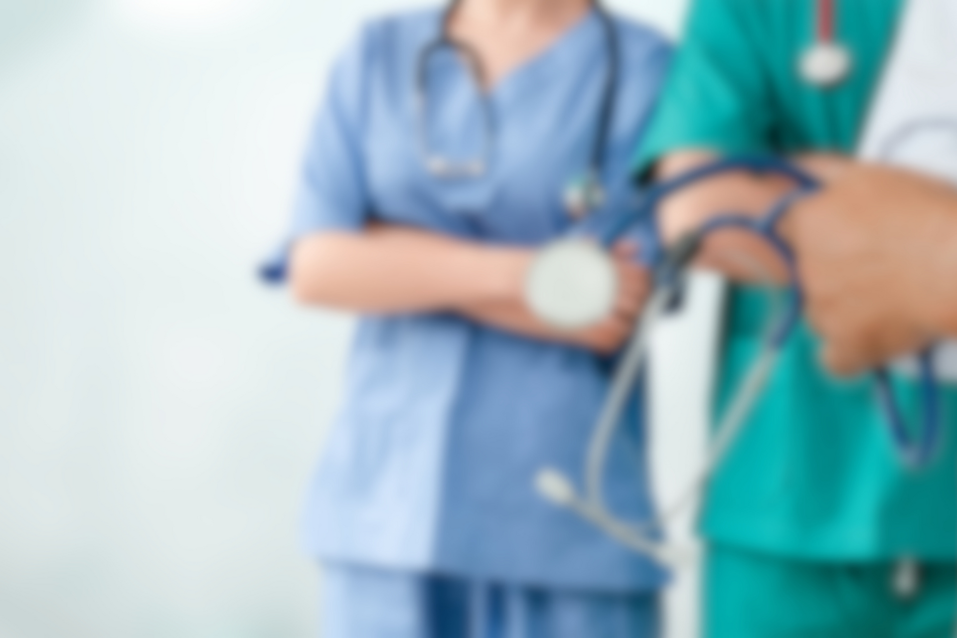 Two medical professionals in scrubs, one blue and one green, with stethoscopes.