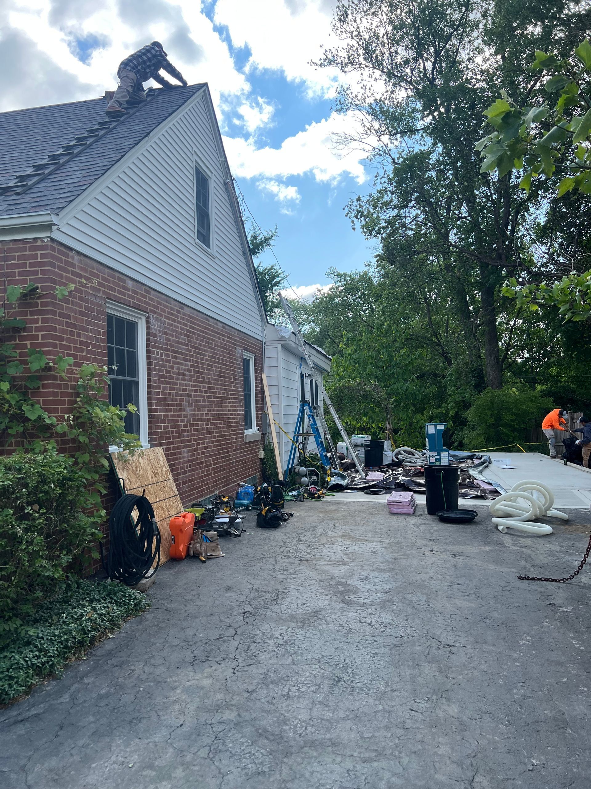A man is working on the roof of a brick house.